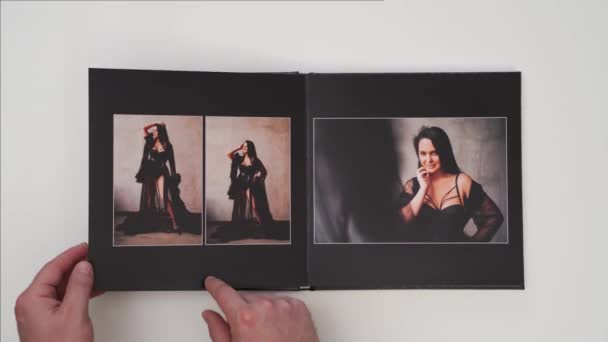 Hände blättern in einem Fotobuch vom Fotoshooting einer Frau auf weißem Hintergrund. — Stockvideo