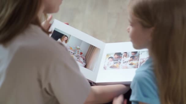 Ovanifrån. mor och dotter letar bok med bilder från familjen fotografering — Stockvideo