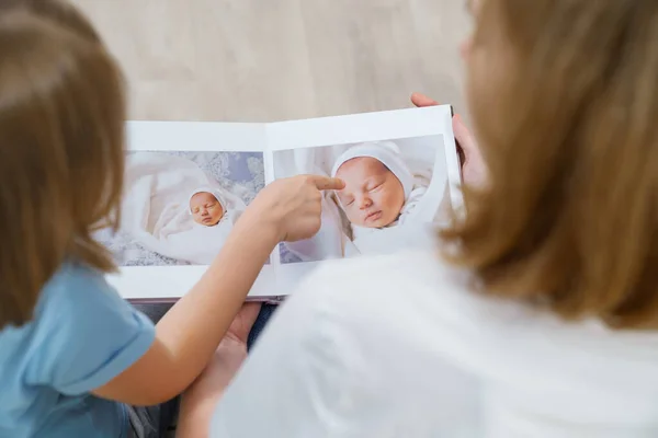 Vista superior. mãe e filha assistir photobook de descarga do bebê recém-nascido — Fotografia de Stock