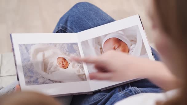 Vista superior. madre e hija ven el libro de fotos del alta del bebé recién nacido — Vídeo de stock