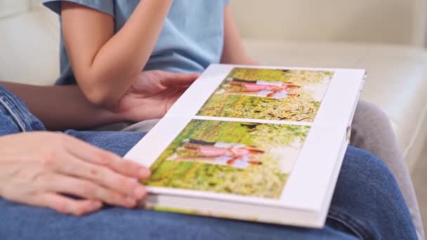 Närbild.mor och dotter titta på fotobok familj fotografering i vår trädgård — Stockvideo
