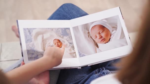 Ansicht von oben. Mutter und Tochter sehen Fotobuch von der Entlassung des Neugeborenen — Stockvideo