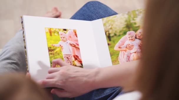 Top view.mother and daughter watch photobook family photo shoot in spring garden — Stock Video