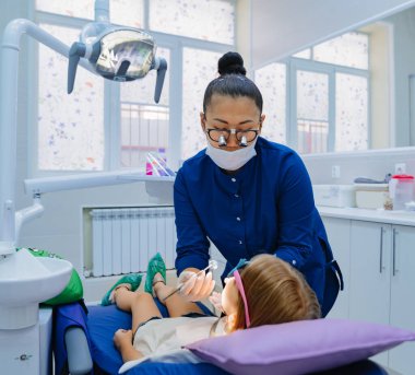 Dişçi bir kızın ağzını muayene eder.. 