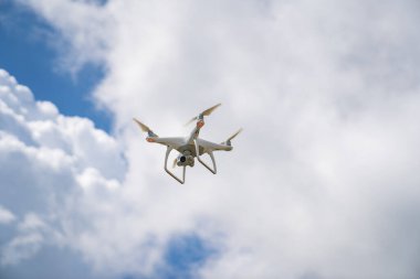 Beyaz bir dron mavi gökyüzünde uçar ve bir video çeker.. 