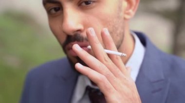 Kapat. Sakallı bir adam ağaçların orada sigara içiyor..