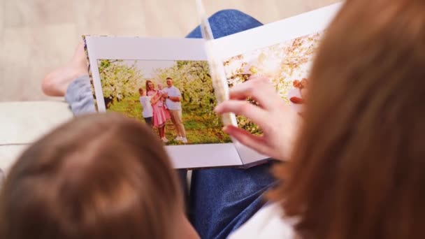 ท็อปวิว แม่และลูกสาวดูภาพถ่ายครอบครัวโฟโต้บุ๊คในสวนฤดูใบไม้ผลิ — วีดีโอสต็อก