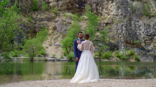 Zachte en liefdevolle pasgetrouwden aan de oever van een bergmeer. — Stockvideo