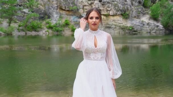 Krásná nevěsta v bílých šatech na břehu horského jezera. — Stock video