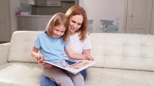 Madre e figlia guardare photobook servizio fotografico di famiglia in giardino primaverile — Video Stock