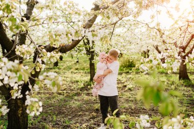 Ağabey, kız kardeşini bahar çiçek bahçesinde tutuyor. Dudak dudağa ameliyattan sonra kız