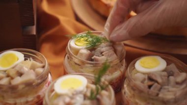 Yemek işi. Kavanozların üzerine tuzlanmış ringa salatası konur..