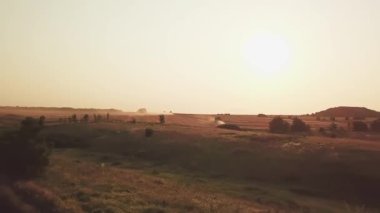 Yaz tarlaları gün batımında hasat sırasında. traktörler ve kombinasyon çalışmaları.