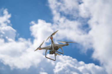 Beyaz bir dron mavi gökyüzünde uçar ve bir video çeker.. 