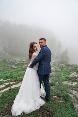 Yeni evliler sisli dağ ormanlarında sarılıyorlar. Yolculukta düğün