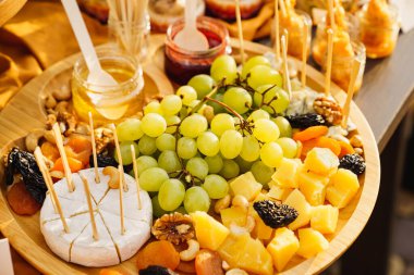 Üzümlü peynirler, kurutulmuş meyveler, fındık, bal ve reçel ahşap bir tabakta..