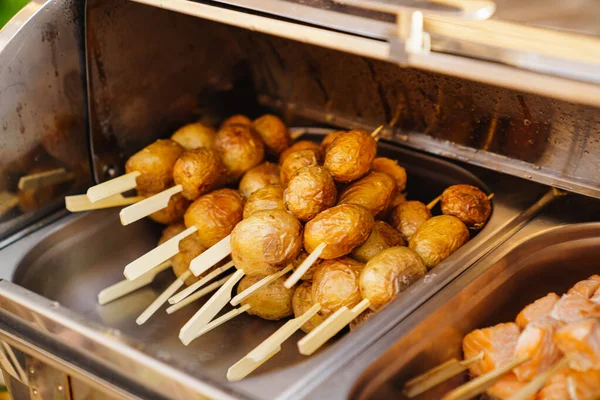 Servindo pequenos kebabs quentes de batatas no buffet. — Fotografia de Stock