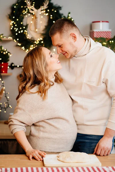 Hermosa mujer embarazada con su marido en la cocina de Año Nuevo prepara la masa. — Foto de Stock