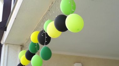 yeşil, sarı ve siyah balonlar terasın tavanında bir çelenkle.