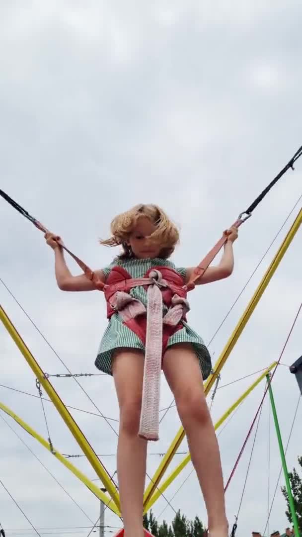 Verticale video. Meisje springt op bungee trampoline. entertainment in het park — Stockvideo