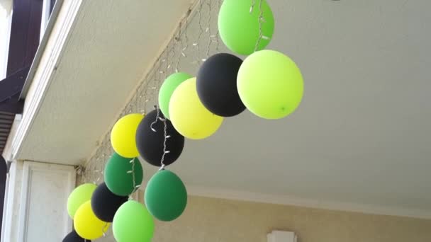 Zelené, žluté a černé balónky na stropě terasy s věncem. — Stock video