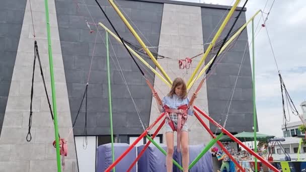 Dospívající dívka skočí na bungee trampolínu. zábava pro děti v parku. — Stock video