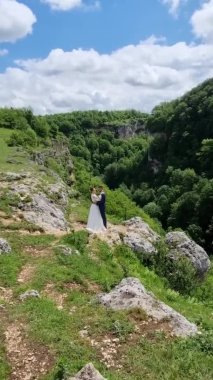 dikey video. Gelin ve damat dağlarda gelinlik içinde.