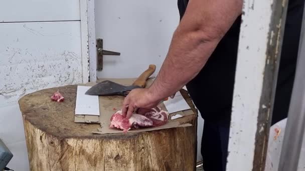 Un hombre corta un trozo de carne con un hacha. carniceros trabajo. — Vídeos de Stock