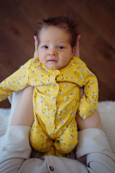 Στην κορυφή. νεογέννητο σε μια κίτρινη φόρμα βρίσκεται στα χέρια moms — Φωτογραφία Αρχείου