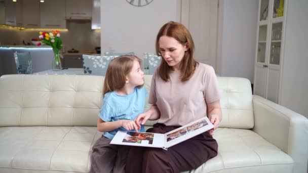 Mutter und Tochter schauen sich ein Buch mit Fotos von einem Familienfotoshooting an — Stockvideo