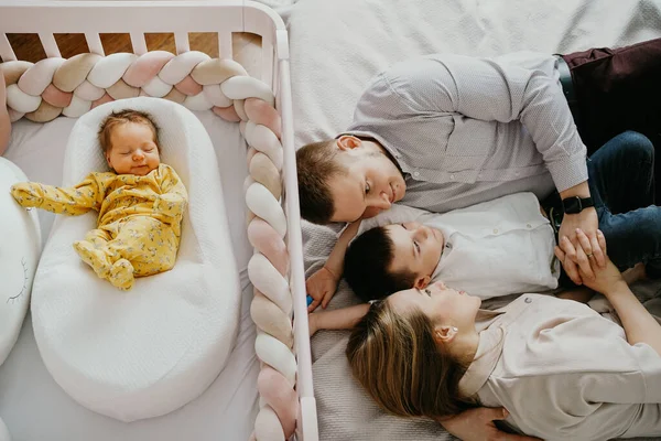 Una familia con un hijo mayor yace en la cuna con un bebé recién nacido. — Foto de Stock