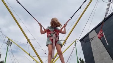 Bir kız çocuğu bungee trambolinde zıplıyor. parkta çocuklar için eğlence.