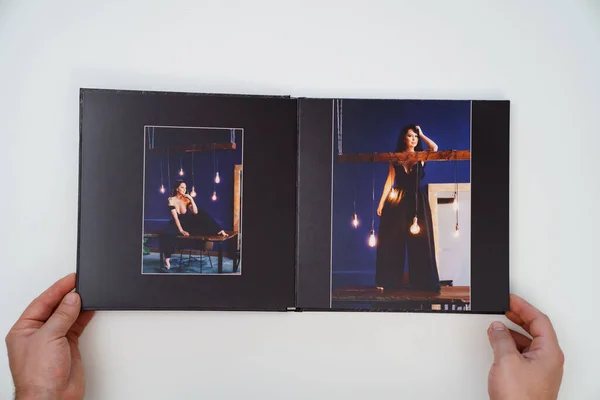 Руки держат открытую фотокнигу с фотосессии женщины на белом фоне. — стоковое фото