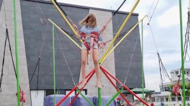Genç bir kız bungee trambolinde zıplıyor. parkta çocuklar için eğlence.