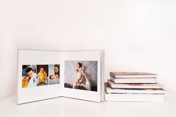 Sobre mesa blanca libro de fotos abierto de sesión de fotos de la familia con el recién nacido. —  Fotos de Stock