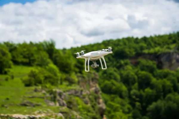 Un dron blanco vuela sobre las montañas y dispara un video. — Foto de Stock