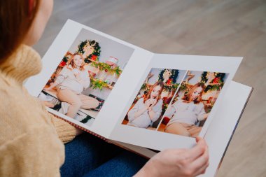 Üst Manzara. Kadın, hamileliğin fotoğraf çekiminden kalma sayfaları karıştırıyor.