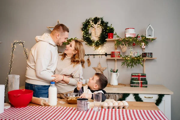 Um rapazinho bate a massa com um batedor. família em conjunto prepara-se para o Ano Novo — Fotografia de Stock