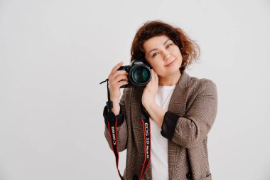 Tişörtlü esmer kadın ve kameralı beyaz arka planda damalı ceket.