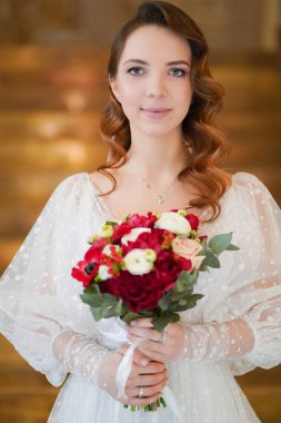 Uzun bukleli bir gelin portresi, zarif bir elbise ve bir buket