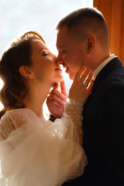 Silhouettes de la mariée et le marié à la lumière du soleil à travers le verre dans la porte. — Photo