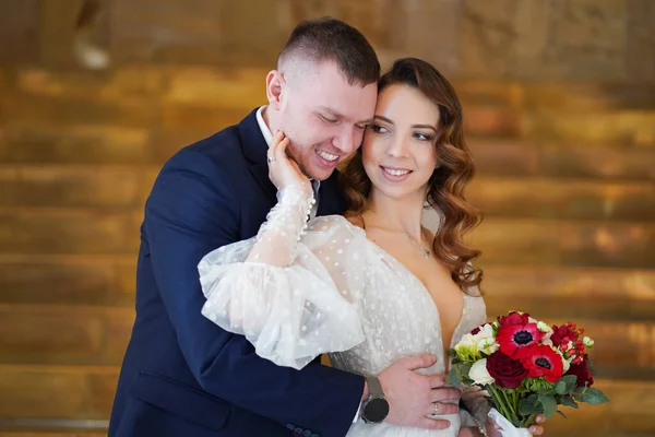 Una bella coppia di sposi con un bouquet. sposa accarezza delicatamente lo sposo sul viso — Foto Stock