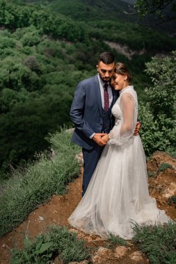 Dağlarda bir düğün töreninde yeni evlilere sarılan güzel bir çift.