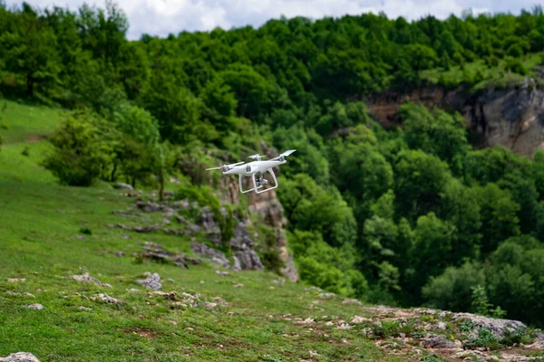 Un dron blanco vuela sobre las montañas y dispara un video. — Foto de Stock
