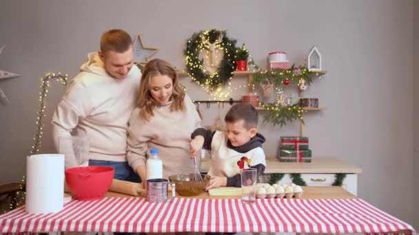 Mały chłopiec bije ciasto trzepaczką. rodzina razem przygotowuje się do nowego roku — Wideo stockowe