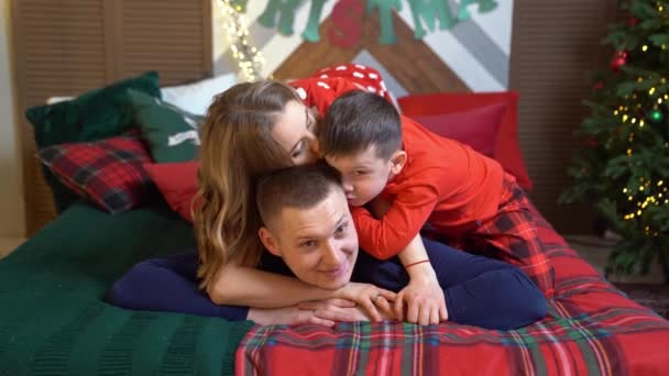 Hermosa familia feliz en pijama en la cama de año nuevo. — Vídeos de Stock
