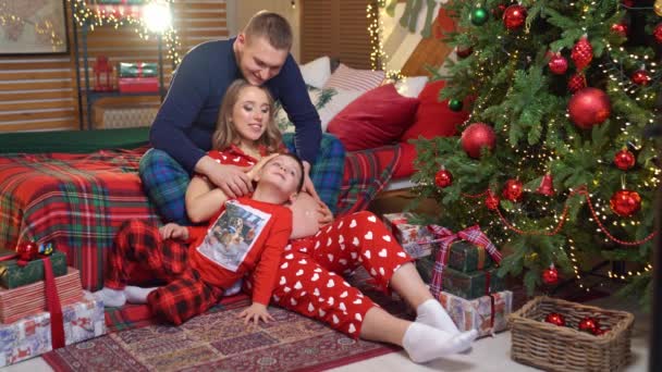 Hermosa familia feliz en pijama en el dormitorio de Año Nuevo. embarazo — Vídeos de Stock