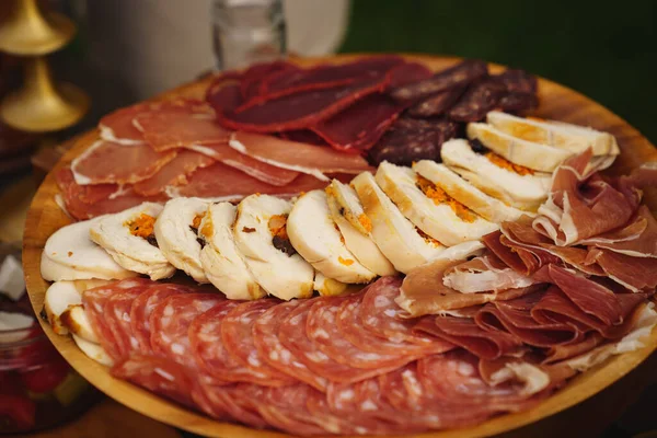 Cortes variados de carne. salchichas, pastel de carne, jamón en un plato redondo de madera. —  Fotos de Stock