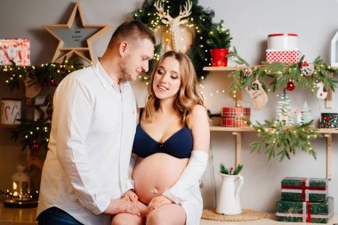 Güzel hamile bir kadın ve beyaz gömlekli bir adam yeni yıl mutfağında..