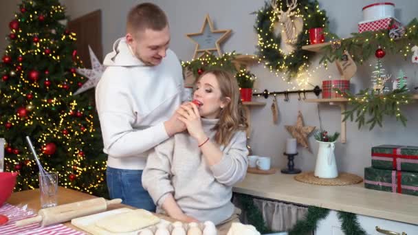 Mulher grávida com marido na cozinha de Ano Novo preparam a massa de farinha e comem bolos — Vídeo de Stock